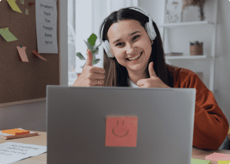 A woman with headphones on and thumbs up.