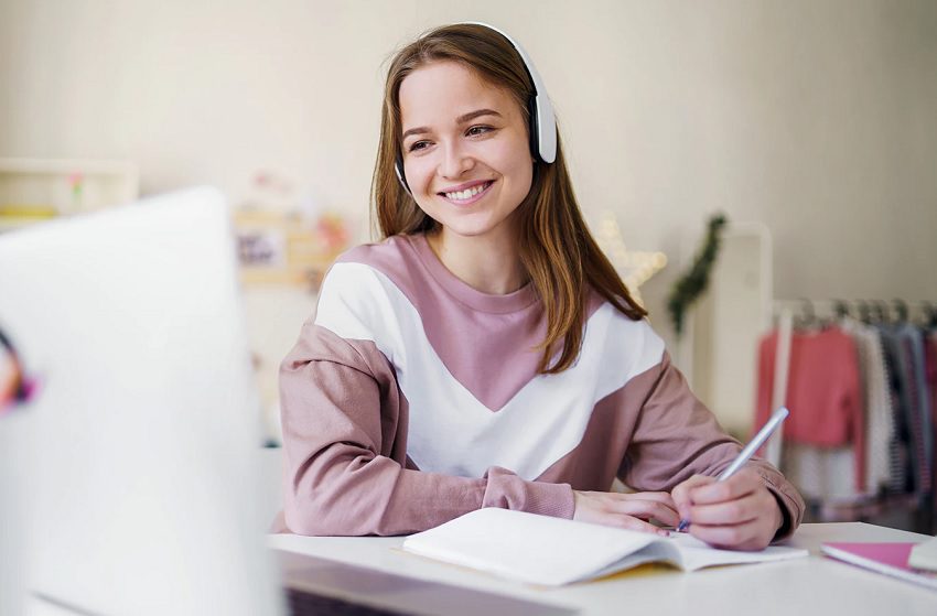 A girl with headphones on sitting at her desk