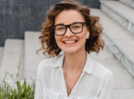 A woman with glasses smiling for the camera.